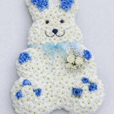 Bunny Rabbit - At Sarah Coxon Floral Design we are delighted to present this product available for flower delivery in Mid and North Norfolk. 

This specialised tribute is a cute Bunny Rabbit and is based in white chrysanthemeums. The spray on the Rabbit  is a small cluster of Roses and Gypsophillia, and the Paws and Ears are sprayed blue (or pink) carnations and Roses. The Rabbit comes complete with a Ribbon and bow around the neck.

You can choose the colour of the ears and paws, please specify the colour of the ribbon and flowers you would like.

This stunning floral display has been arranged in water retaining foam (oasis) to ensure maximum freshness. 

We deliver directly to all of the local funeral directors and will contact them to confirm a delivery time. 

Our flowers at Sarah Coxon Floral Design arrive fresh from the Dutch auctions every day so you can be rest assured we are using the best quality of flowers available.