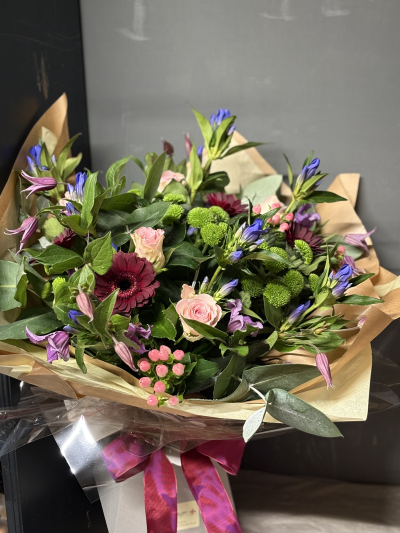 Jewel Hand Tied - A stunning display of flowers in plum, pink, blue and lime green.

This is gift wrapped and arrives in a water bubble concealed in a box.